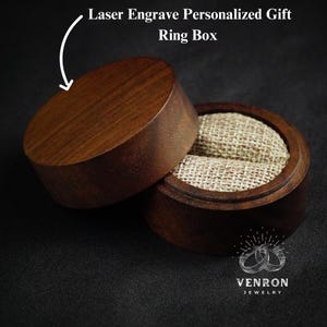May include: A wooden ring box with a lid. The box is made of dark brown wood and has a natural wood grain. The inside of the box is lined with a beige fabric. The box is closed and the lid is on top of the box. The text "Laser Engrave Personalized Gift Ring Box" is written above the box.