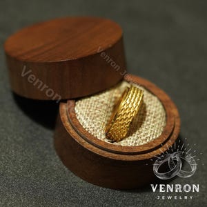 May include: A gold ring with a textured design sits inside a wooden ring box with the words "Venron Jewelry" printed on the side.