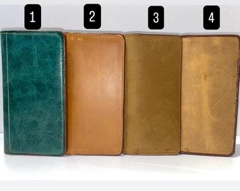 May include: Four leather wallets in various shades of brown and green. The wallets are rectangular and appear to be closed. The first wallet is a deep teal green, the second is a light brown, the third is a medium brown, and the fourth is a darker brown.