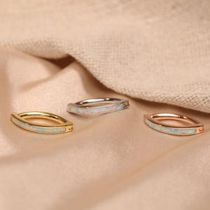 May include: Three hoop earrings with opal inlay. The hoops are made of gold, silver, and rose gold.