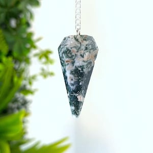 Op de afbeelding: Een gefacetteerde, kegelvormige mosagaat hanger hangend aan een zilverkleurige metalen ketting. De steen heeft een gepolijst oppervlak met ingewikkelde, wervelende patronen van diep bosgroen, doorschijnend wit en subtiele aardse bruine tinten.