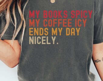 May include: A gray t-shirt with the text "MY BOOKS SPICY MY COFFEE ICY ENDS MY DAY NICELY." printed in a retro-style font with orange, red, and yellow colors.