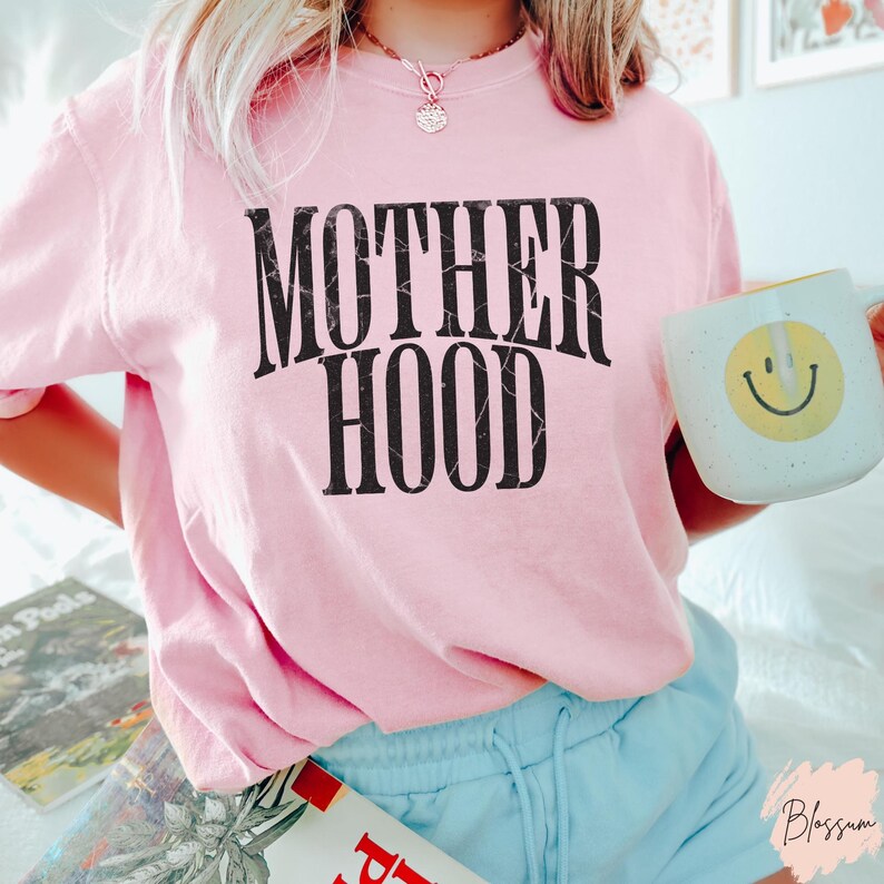 May include: Pink t-shirt with the text "MOTHERHOOD" in black with a marbled effect.