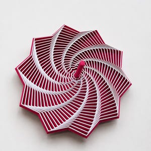 May include: A multi-layered, star-shaped object featuring a repeating geometric pattern of magenta and white concentric rings that spiral towards a central magenta post. The structure creates a deep, layered visual effect with sharp edges.
