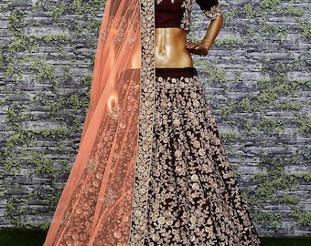 May include: A maroon lehenga choli set with gold floral embroidery. The set includes a short-sleeved top, a full skirt, and a peach-coloured sheer dupatta. The outfit is displayed on a mannequin.