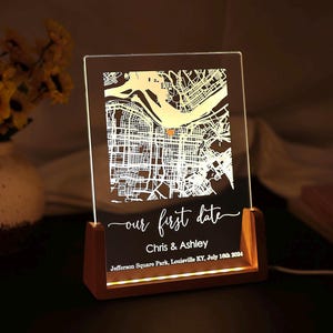 May include: A wooden light-up sign with a map of a city and the text "our first date Chris & Ashley Jefferson Square Park, Louisville KY, July 16th 2004".