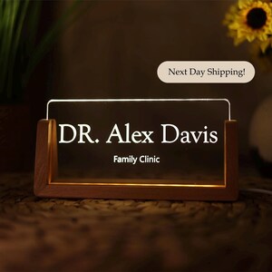 May include: A wooden sign with a clear acrylic insert that lights up. The sign says "DR. Alex Davis Family Clinic".