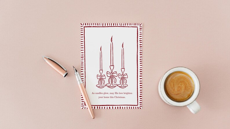 K&ouml;nnte beinhalten: Eine Weihnachtskarte mit rotem Rand und einer Zeichnung von drei Kerzen, einem Stift und einer Tasse Kaffee auf rosa Hintergrund. Auf der Karte steht: &bdquo;M&ouml;ge seine Liebe Ihr Zuhause an diesem Weihnachten erhellen.&ldquo;