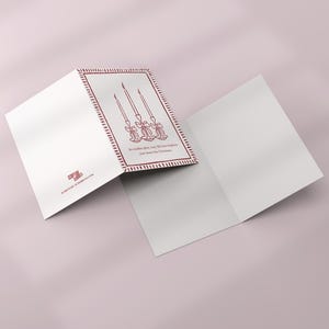 K&ouml;nnte beinhalten: Eine wei&szlig;e Weihnachtskarte mit rotem Rand und Kerzenillustration. Die Karte ist ge&ouml;ffnet und zeigt einen leeren Innenraum. Auf der Karte steht: "M&ouml;gen die Kerzen leuchten, m&ouml;ge die Liebe Ihr Zuhause an diesem Weihnachten erhellen."