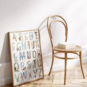 May include: A framed alphabet poster with illustrations for each letter. The poster has a white background with light blue, brown, and yellow accents. The letters are in a large, bold font. The illustrations are of various animals, objects, and people.