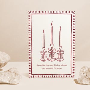 K&ouml;nnte beinhalten: Eine Weihnachtskarte mit einem weinroten Rand und einem cremefarbenen Hintergrund. Die Karte zeigt eine Strichzeichnung von drei Kerzen mit Schleifen. Der Text lautet: &bdquo;Wenn Kerzen leuchten, m&ouml;ge Seine Liebe Ihr Zuhause an diesem Weihnachten erhellen.&ldquo;