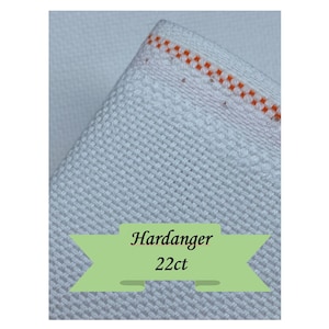 K&ouml;nnte beinhalten: Nahaufnahme eines wei&szlig;en Hardanger-Stoffs mit strukturiertem Gewebe. Der Stoff hat einen Rand mit orangefarbenen N&auml;hten. Der Text "Hardanger 22ct" wird auf einem gr&uuml;nen Banner angezeigt.