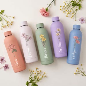 Puede incluir: Cinco botellas de agua coloridas con diseños florales y nombres: Ava, Emma, Harper, Sophia y Evelyn. Las botellas son de color melocotón, blanco, verde, lila y azul. Cada botella tiene una ilustración floral diferente y una tapa del mismo color.