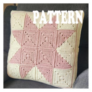 May include: A square crochet pillow with a star design in the center. The star is made of pink yarn, and the background is cream-colored. The word "PATTERN" is displayed in white block letters across the top of the pillow.