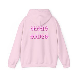 May include: Pink hooded sweatshirt with the text "JESUS SAVES" in a gothic font printed on the back.
