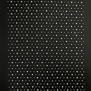 May include: A black fabric background with a pattern of small, white, evenly spaced dots.