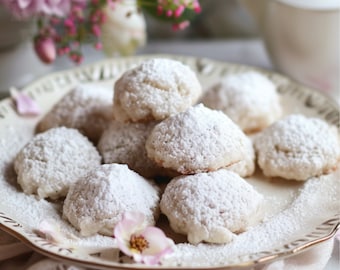 May include: A plate of white powdered sugar cookies on a white background with pink flowers.