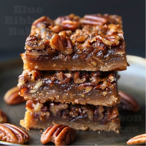 Op de afbeelding: Een stapel van vier pecan-taartreepjes met een knapperige korst en een kleverige pecanvulling. De reepjes zijn gerangschikt op een donkerbruin bord met een paar verspreide pecannoten.
