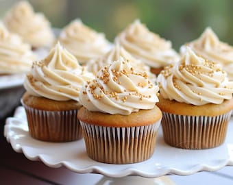 May include: A close-up of a plate of cupcakes with vanilla frosting and gold sprinkles. The cupcakes are arranged in a circle on a white cake stand.