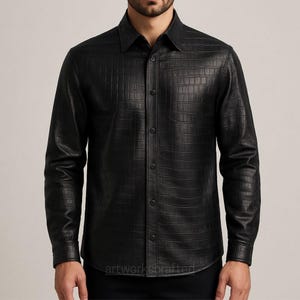 Op de afbeelding: Zwart overhemd met knopen en een krokodillenleertextuur. Het shirt met lange mouwen heeft een klassieke kraag en manchetten met knopen. Het shirt is gemaakt van een donker, glanzend materiaal. De merknaam "artworkscrafted" is onderaan zichtbaar.