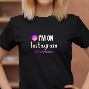 Könnte beinhalten: Schwarzes T-Shirt mit weißem Text, der "I'm on Instagram @Username" lautet, und einem stilisierten Instagram-Logo in Pink, Orange und Lila.
