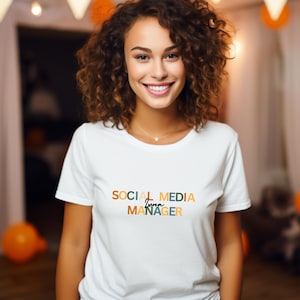 May include: A white t-shirt with the text "SOCIAL MEDIA Luna MANAGER" in colourful, overlapping letters. The text is in a modern, stylised font.