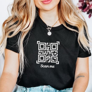 May include: A black t-shirt with a white QR code and the text "Scan me" printed on the front.