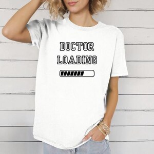 May include: White t-shirt with black text that reads "DOCTOR LOADING" and a progress bar underneath.