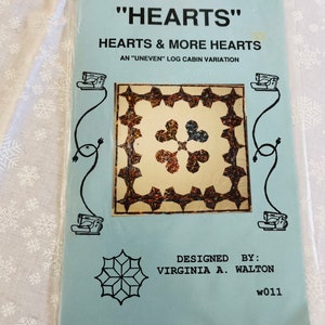May include: A blue and white quilt pattern with the title "Hearts & More Hearts" and the text "An "Uneven" Log Cabin Variation". The pattern is designed by Virginia A. Walton and has the number w011.