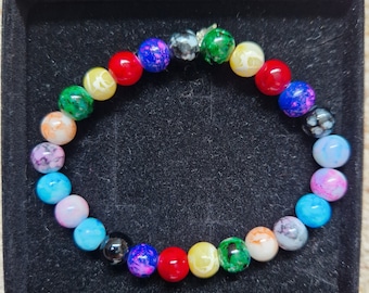 May include: A colorful beaded bracelet with a variety of colors, including blue, green, red, yellow, and white. The beads are round and have a speckled or marbled appearance.
