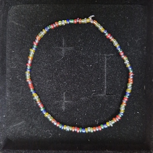 May include: A multi-coloured beaded necklace with silver, red, blue, green, and yellow beads.
