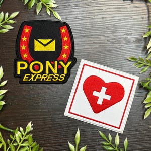 May include: Two embroidered patches. One features a black horseshoe shape with a yellow envelope, red stars, and the words "PONY EXPRESS" in yellow. The other is a white square with a red heart and a white cross.