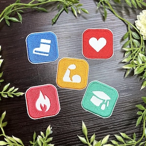 Puede incluir: Cinco parches bordados con bordes cuadrados. Los parches presentan iconos de una bota, un corazón, un brazo flexionándose, una llama y un birrete. Los parches son azules, rojos, amarillos y verdes con costuras blancas y rojas.