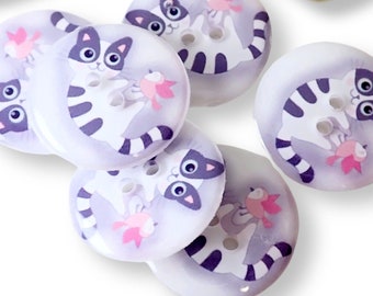 May include: Six white plastic buttons with a cartoon cat design. Each button features a black and white striped cat holding a pink fish. The buttons are approximately 1 inch in diameter.