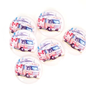 May include: A set of clear, circular buttons. Each button displays a watercolour illustration of a red and white RV, adorned with a Canadian flag. The RV has a white roof and is set against a light background.