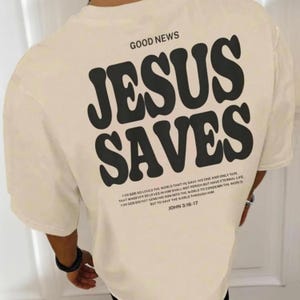 May include: A beige t-shirt with a black graphic that says "GOOD NEWS JESUS SAVES" and a Bible verse from John 3:16-17.