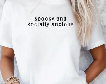 May include: White t-shirt with the text "spooky and socially anxious" in a black, simple font. The shirt is short-sleeved and appears to be made of a soft material.