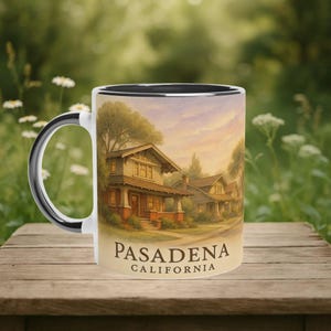 Può includere: Tazza in ceramica bianca con interno e manico neri, con un'illustrazione dettagliata di case e la scritta "PASADENA CALIFORNIA". L'opera raffigura una scena di strada residenziale con alberi e un tramonto.