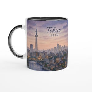 May include: White ceramic mug with a black interior and handle. The mug features a watercolor illustration of Tokyo, Japan, with the Tokyo Skytree and city skyline. The text "Tokyo JAPAN" is printed on the mug.