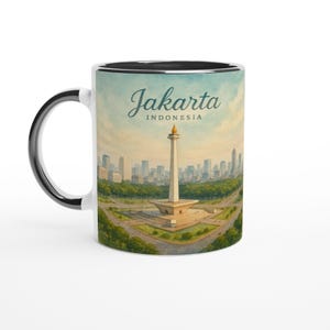 Può includere: Tazza in ceramica bianca con interno e manico neri. La tazza presenta un'illustrazione ad acquerello dello skyline di Giacarta, con il testo "Jakarta INDONESIA" in un carattere corsivo.