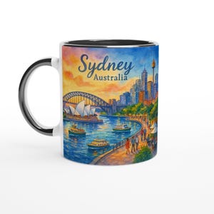 May include: White ceramic mug with a black handle and rim, featuring a colorful illustration of Sydney, Australia. The design includes the Sydney Opera House, Harbour Bridge, and city skyline, with the text "Sydney Australia".