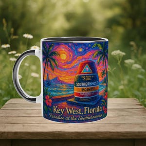 May include: White ceramic mug featuring a colorful painting of Key West, Florida. The design includes palm trees, a sunset, and the Southernmost Point marker. Text on the mug reads "Key West, Florida" and "Paradise at the Southernmost".
