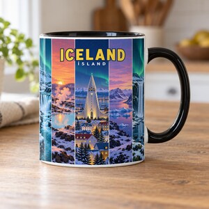 Peut inclure: Un mug en céramique blanc avec une anse et un bord noirs, orné d'un design à panneaux verticaux représentant des paysages islandais, dont l'église Hallgrímskirkja, des cascades et des aurores boréales, avec le texte ICELAND ÍSLAND en haut.