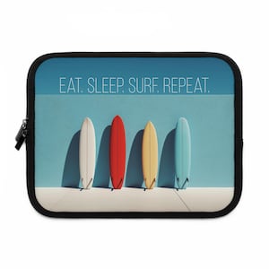 May include: A black laptop sleeve featuring four surfboards in white, red, yellow, and blue against a light blue background. The text "EAT. SLEEP. SURF. REPEAT." is printed above the surfboards. The sleeve has a black zipper.