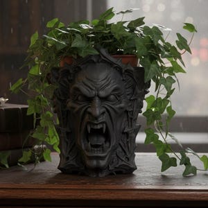 May include: A dark grey, gothic-style planter with a snarling face and sharp teeth, filled with a green plant and trailing vines. A lit candle in a brass holder and antique books sit on a wooden desk, creating a moody, vintage aesthetic.