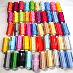 May include: A collection of numerous sewing thread spools in a wide variety of vibrant colors including red, blue, yellow, green, pink, orange, purple, silver, and black. Each spool features a cylindrical shape with white plastic ends.