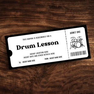 May include: A black and white ticket with the text "THIS COUPON IS REDEEMABLE FOR A Drum Lesson" and "ADMIT ONE". The ticket has a drawing of a drum kit.