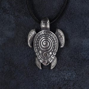 May include: Silver turtle pendant necklace with a black leather cord. The pendant showcases detailed spiral and dot patterns, with intricate flipper and head designs. A stylish accessory for any outfit.