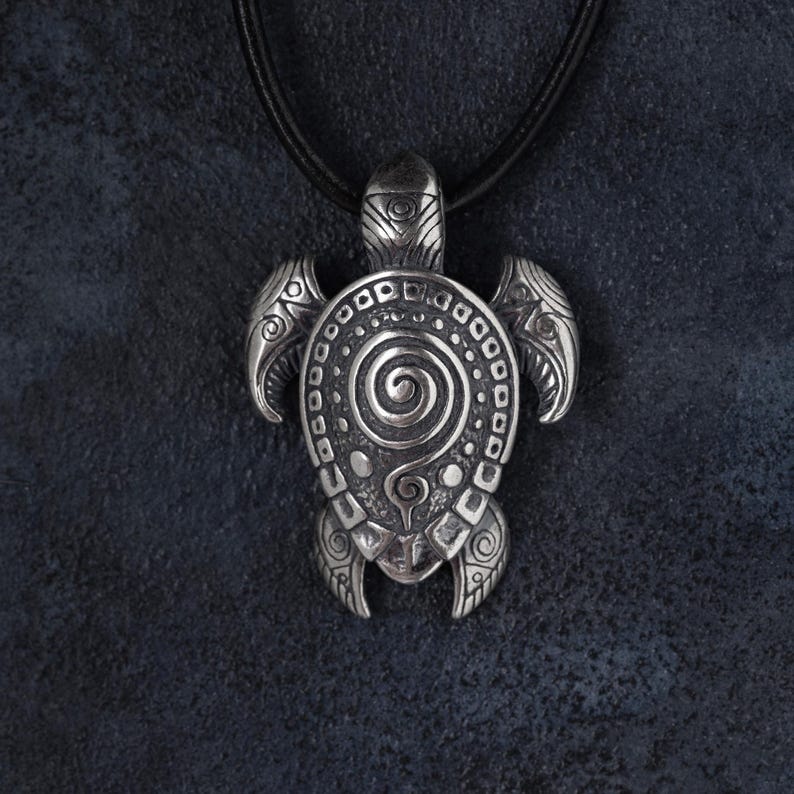 May include: Silver turtle pendant necklace with a black leather cord. The pendant showcases detailed spiral and dot patterns, with intricate flipper and head designs. A stylish accessory for any outfit.