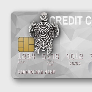 May include: A silver turtle charm sits on a credit card with a geometric design. The card displays the words "CREDIT CARD". The card number is 1234 5678 9012 3456.